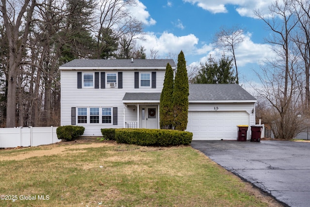 view of front of property with roof with shingles, an attached garage, aphalt driveway, a front yard, and fence