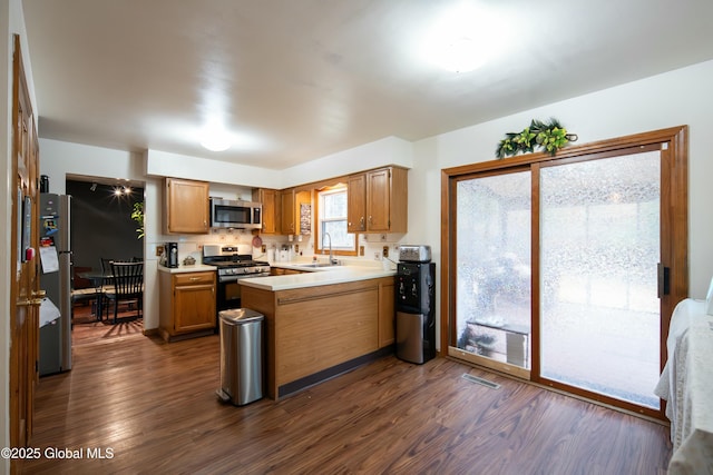 kitchen featuring a peninsula, visible vents, appliances with stainless steel finishes, light countertops, and dark wood-style floors