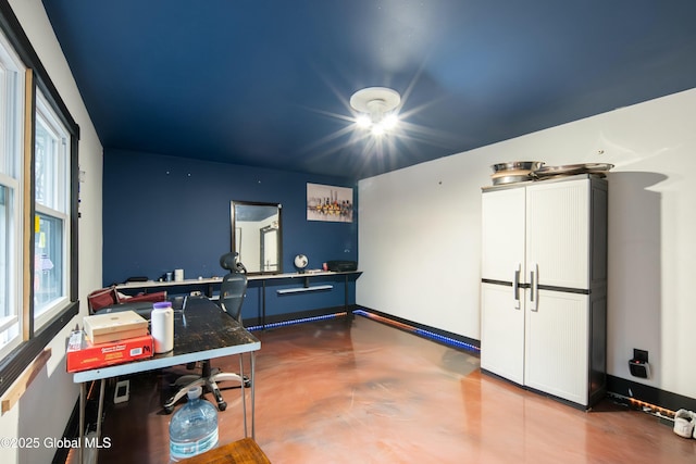 office area featuring finished concrete flooring and baseboards