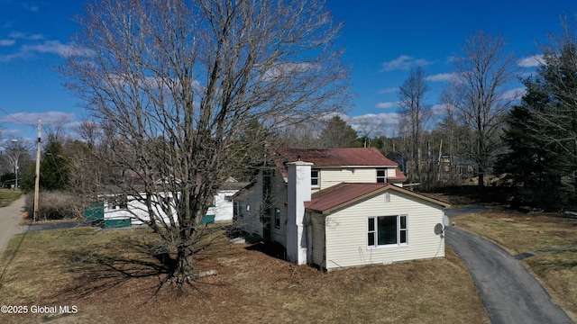 view of side of property featuring metal roof and aphalt driveway