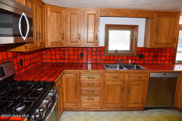 kitchen featuring tasteful backsplash, tile countertops, a sink, and appliances with stainless steel finishes