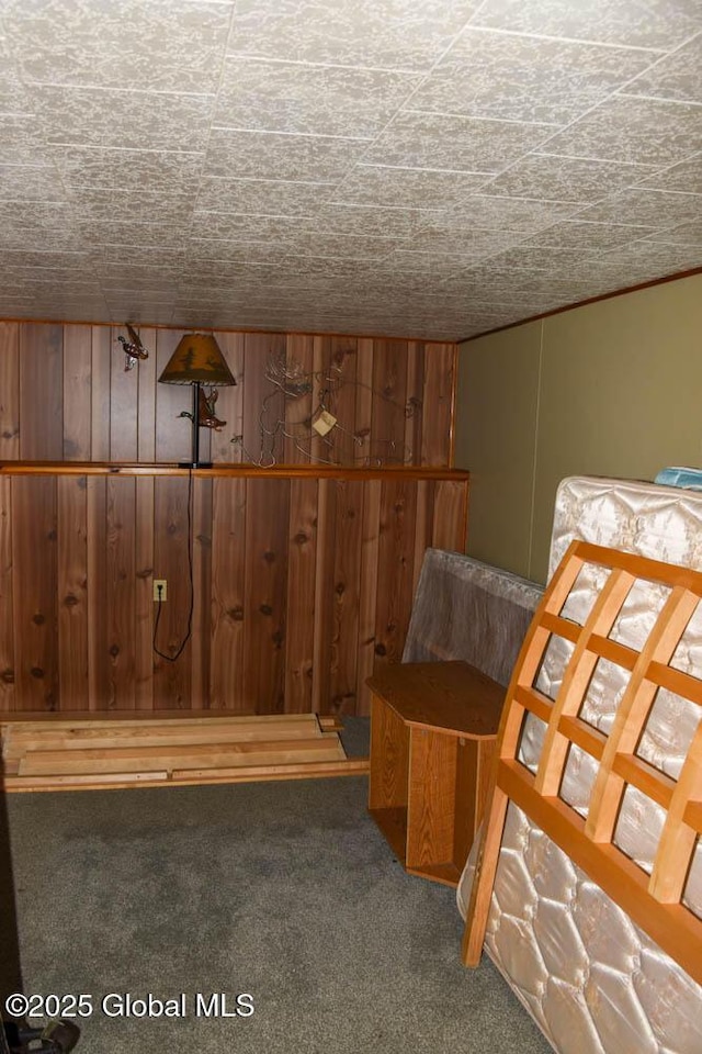 bedroom featuring wooden walls and carpet