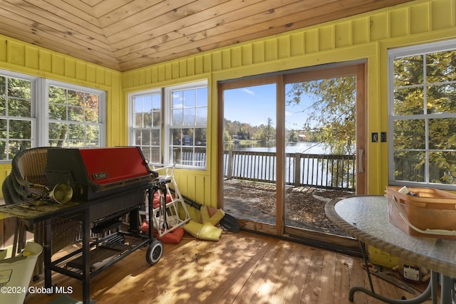 sunroom featuring hardwood / wood-style floors, vaulted ceiling, and a water view