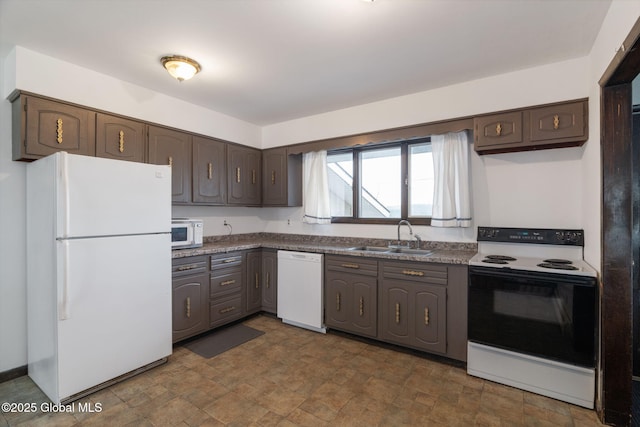 kitchen featuring stone finish floor, dark countertops, dark brown cabinets, a sink, and white appliances