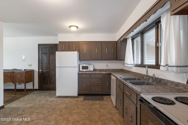 kitchen featuring a sink, stone finish flooring, dark countertops, and white appliances