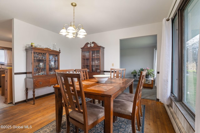 dining room with a baseboard radiator, hardwood / wood-style floors, and a chandelier