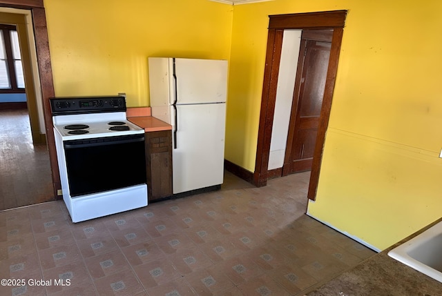 kitchen featuring freestanding refrigerator, electric range, and baseboards
