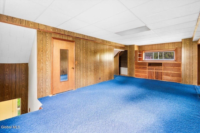 104 Euclid Ave, Altamont, NY 12009 - unfurnished living room featuring wood walls, carpet floors, and a paneled ceiling