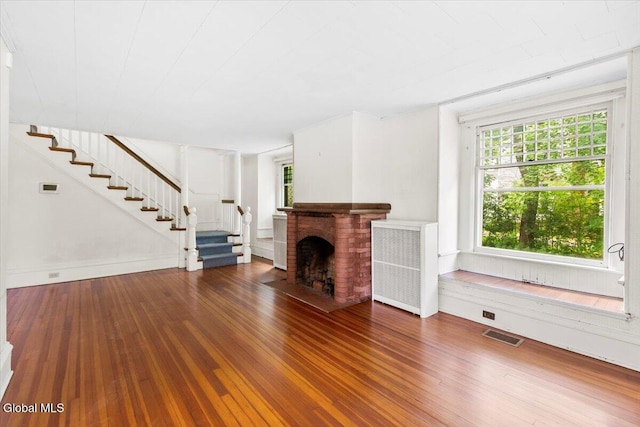 104 Euclid Ave, Altamont, NY 12009 - unfurnished living room with stairway, wood finished floors, and a brick fireplace
