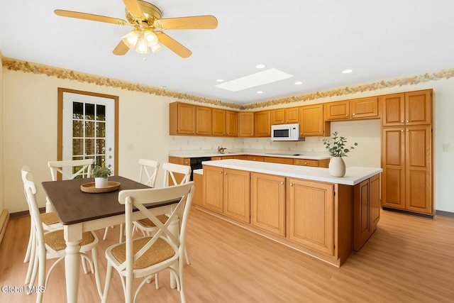 104 Euclid Ave, Altamont, NY 12009 - kitchen with white microwave, light wood-style flooring, light countertops, a kitchen island, and black electric stovetop