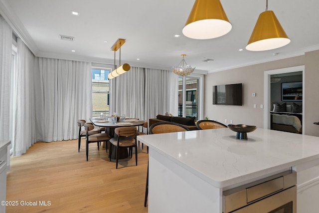 kitchen with visible vents, crown molding, pendant lighting, light wood-style flooring, and light stone counters