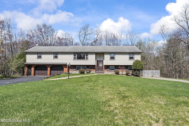 raised ranch with aphalt driveway, a front lawn, and an attached garage