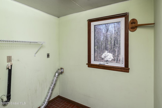 laundry area with brick floor, electric dryer hookup, laundry area, and baseboards