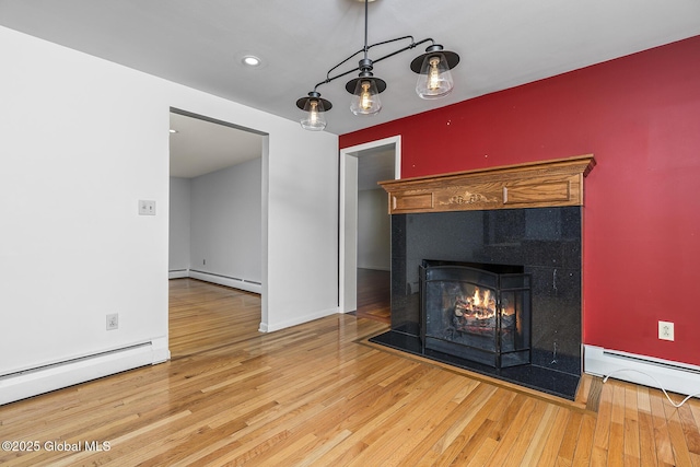 unfurnished living room featuring wood finished floors, a warm lit fireplace, and a baseboard radiator