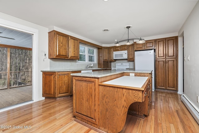 kitchen with brown cabinetry, white microwave, light wood-style flooring, and a baseboard radiator