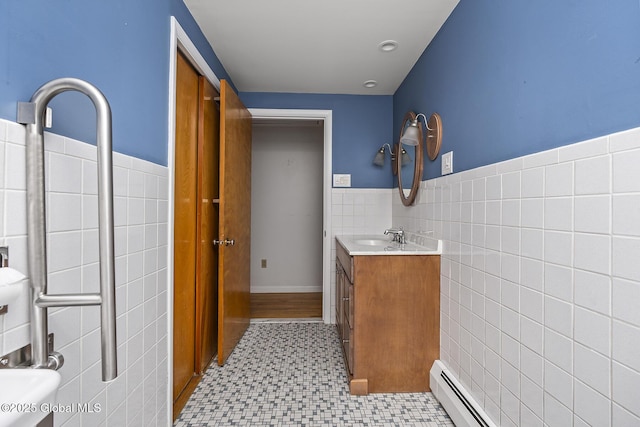bathroom with a baseboard radiator, tile patterned floors, wainscoting, tile walls, and vanity
