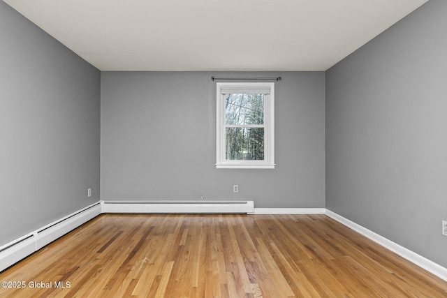unfurnished room featuring baseboards, wood finished floors, and a baseboard heating unit