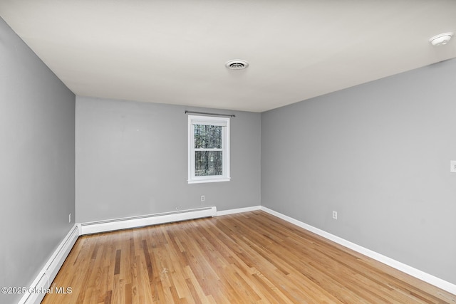 empty room with a baseboard heating unit, visible vents, light wood-style flooring, and baseboards