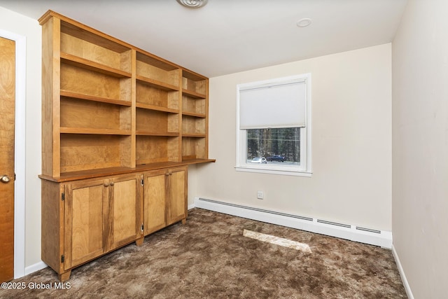 spare room featuring baseboard heating, dark colored carpet, and baseboards