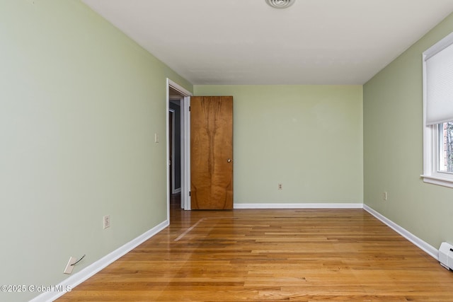 unfurnished room with light wood-style floors, visible vents, and baseboards