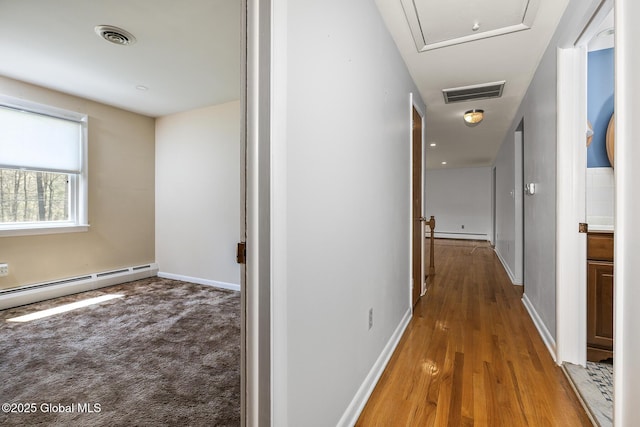 hallway with baseboards, visible vents, baseboard heating, and a baseboard radiator