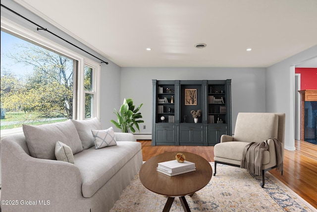 living area with baseboard heating, recessed lighting, and wood finished floors