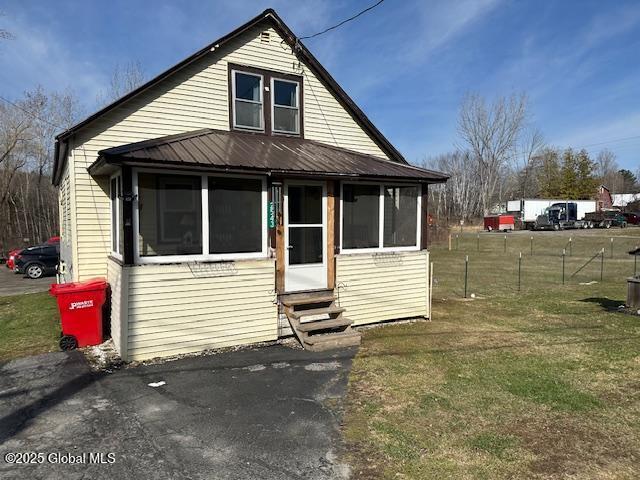 2543 Moriah Rd, Moriah, NY 12960 - bungalow-style house featuring a front yard, entry steps, fence, and a sunroom