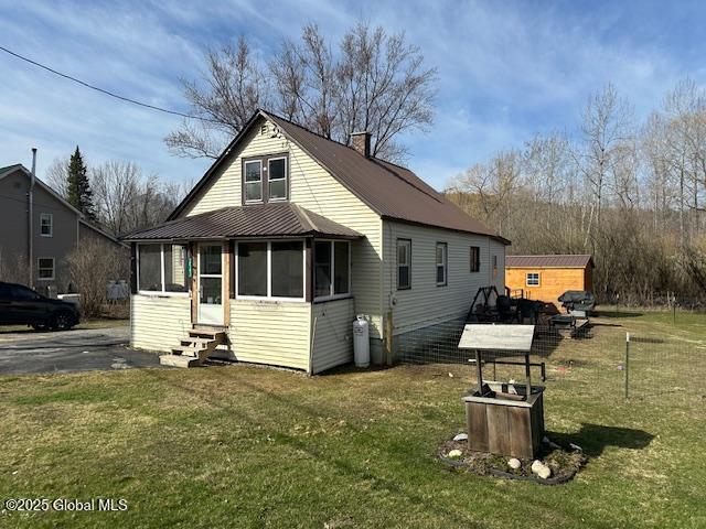 2543 Moriah Rd, Moriah, NY 12960 - view of front facade with entry steps, a front lawn, metal roof, and a chimney