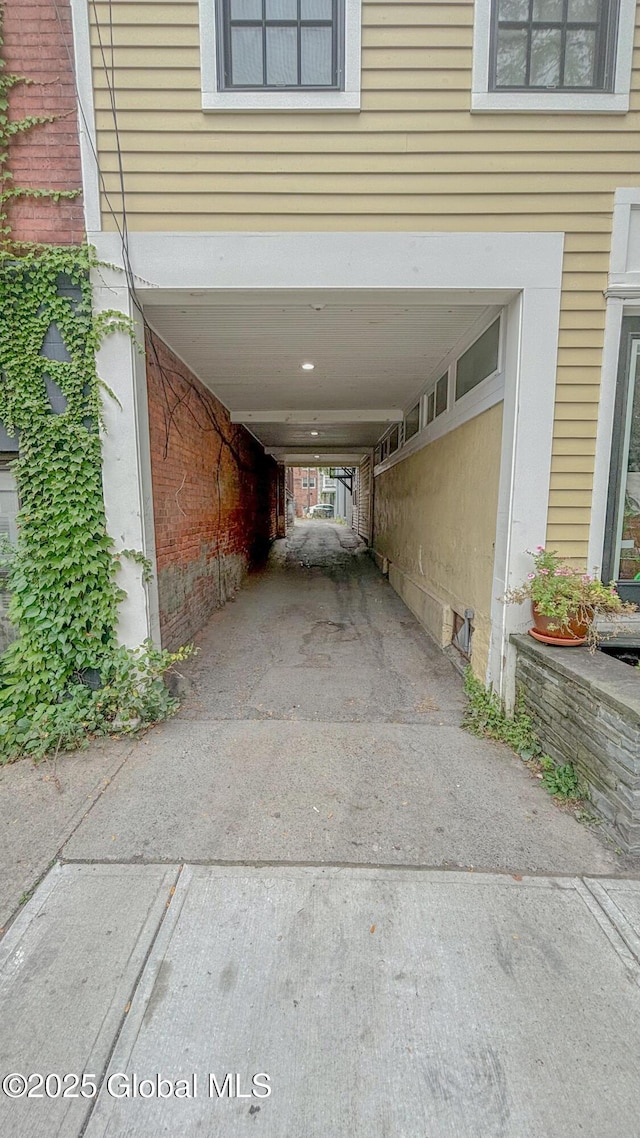 view of car parking with concrete driveway and a carport