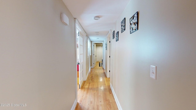 corridor with light wood-type flooring and baseboards