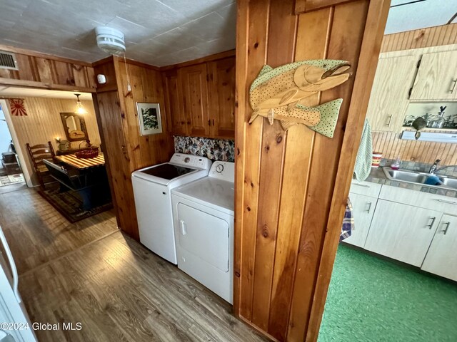 16 Pumphouse Rd, Lake Luzerne, NY 12846 - clothes washing area featuring washer and dryer, wood finished floors, a sink, and cabinet space