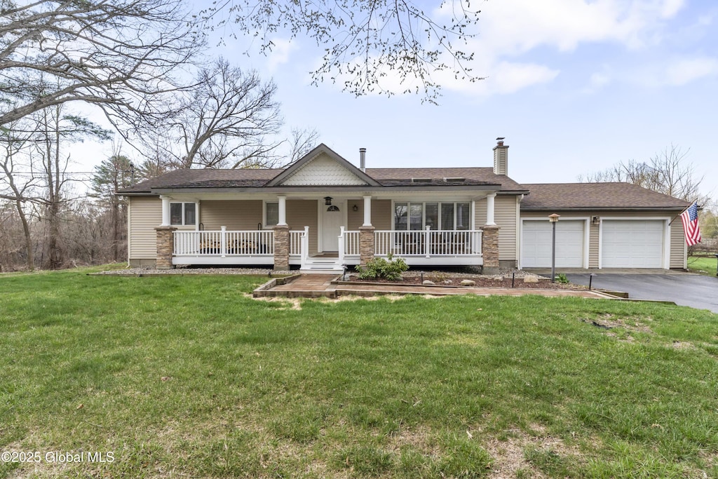 view of front of house with a chimney, a front lawn, driveway, a porch, and a garage