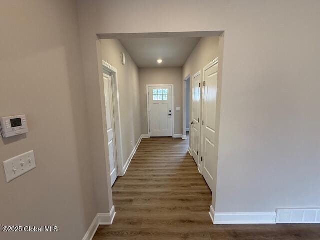 hallway featuring baseboards, dark wood finished floors, and visible vents