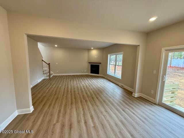 unfurnished living room featuring baseboards, wood finished floors, and a healthy amount of sunlight
