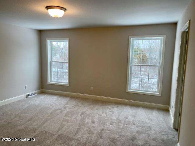 unfurnished room with baseboards and light colored carpet