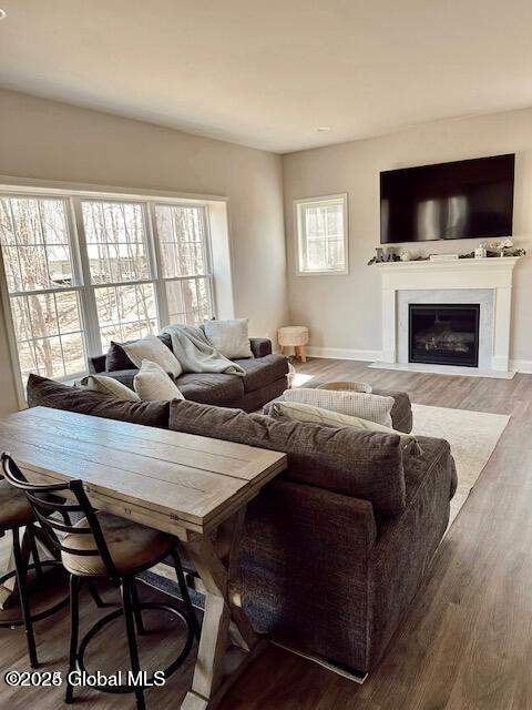 living room featuring a glass covered fireplace, baseboards, and wood finished floors
