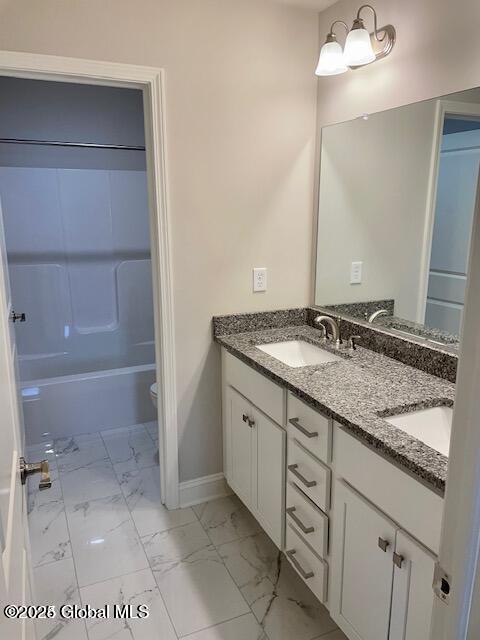bathroom featuring a sink, baseboards, double vanity, and marble finish floor