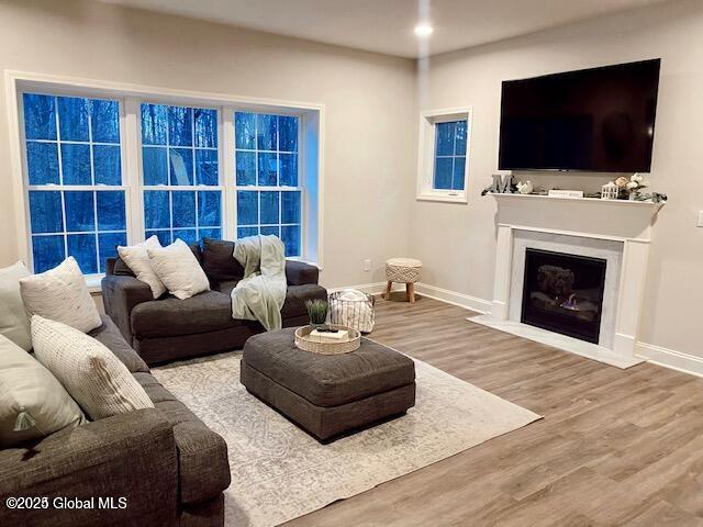 living room featuring a fireplace with flush hearth, wood finished floors, and baseboards