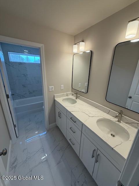 full bath with double vanity, marble finish floor, a sink, and baseboards
