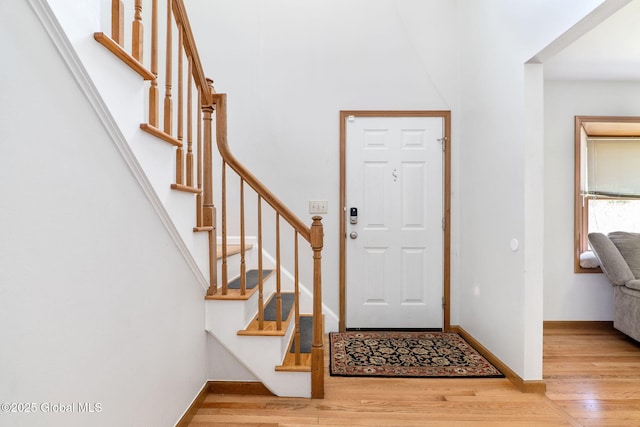 foyer entrance with baseboards, wood finished floors, and stairway