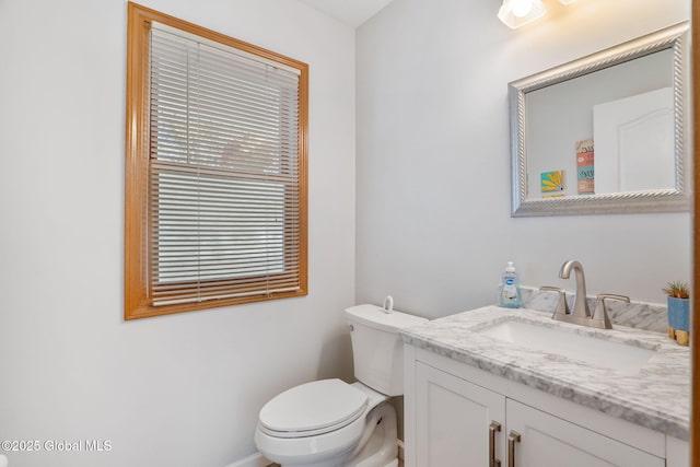 half bathroom featuring vanity, baseboards, and toilet