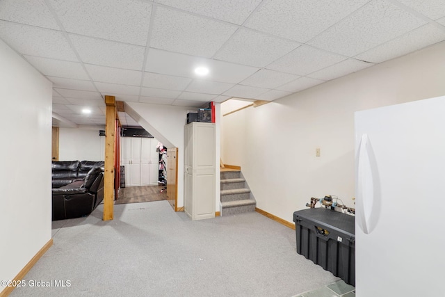 finished basement featuring carpet floors, baseboards, stairway, and a paneled ceiling