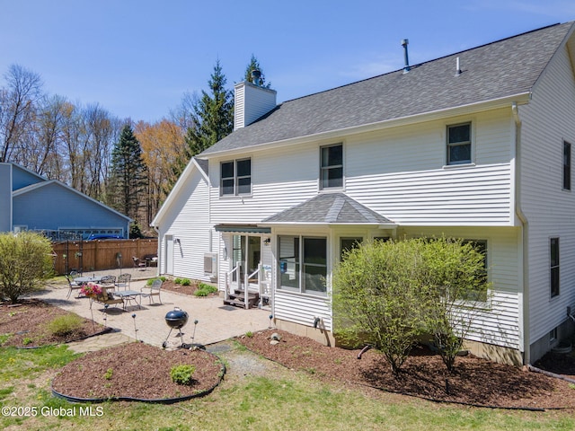 rear view of house featuring a patio, fence, a chimney, and a shingled roof
