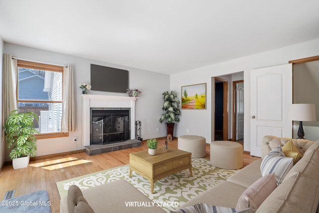 living room with a fireplace with raised hearth, visible vents, and wood finished floors