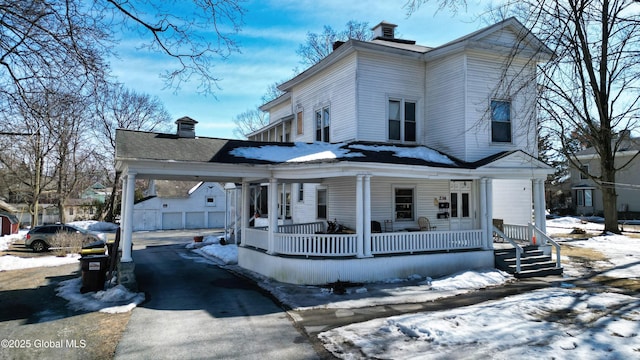 italianate home featuring a chimney, driveway, a carport, an outdoor structure, and a porch