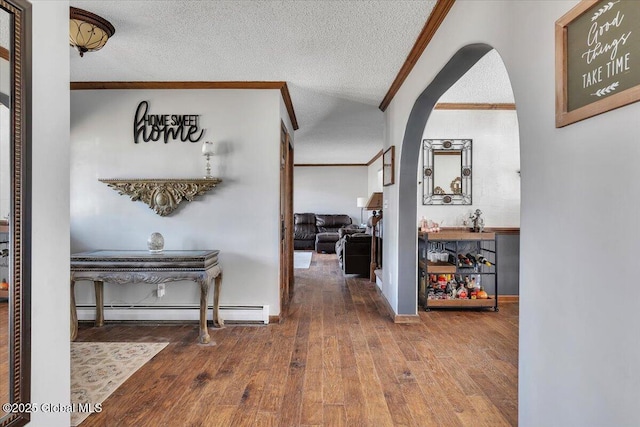 hallway featuring a baseboard heating unit, arched walkways, a textured ceiling, hardwood / wood-style flooring, and ornamental molding