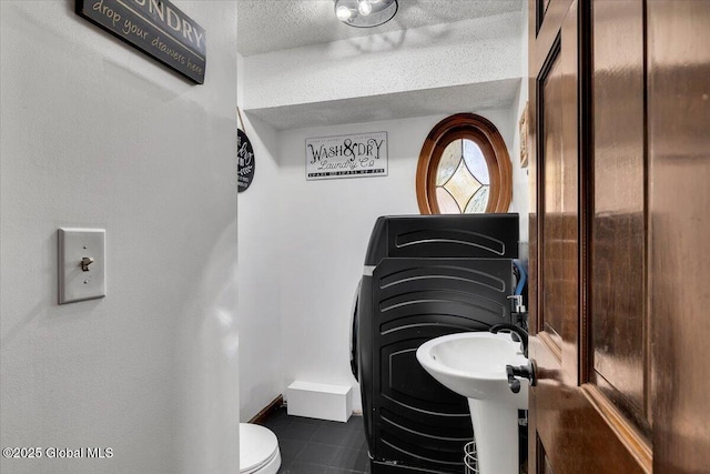 bathroom with a textured ceiling, tile patterned flooring, and toilet