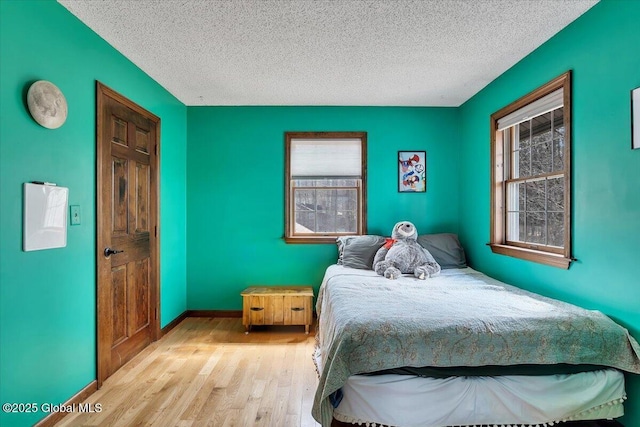 bedroom with baseboards, wood finished floors, and a textured ceiling