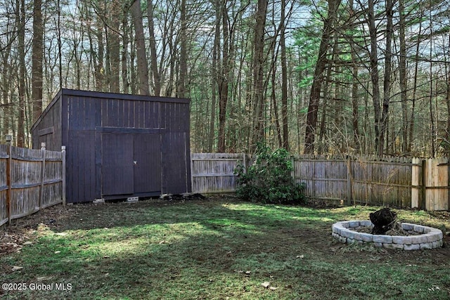 view of yard with a fenced backyard, a view of trees, an outbuilding, and a storage shed