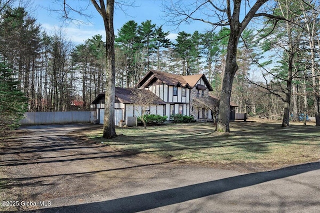 tudor-style house featuring driveway, central AC, and fence